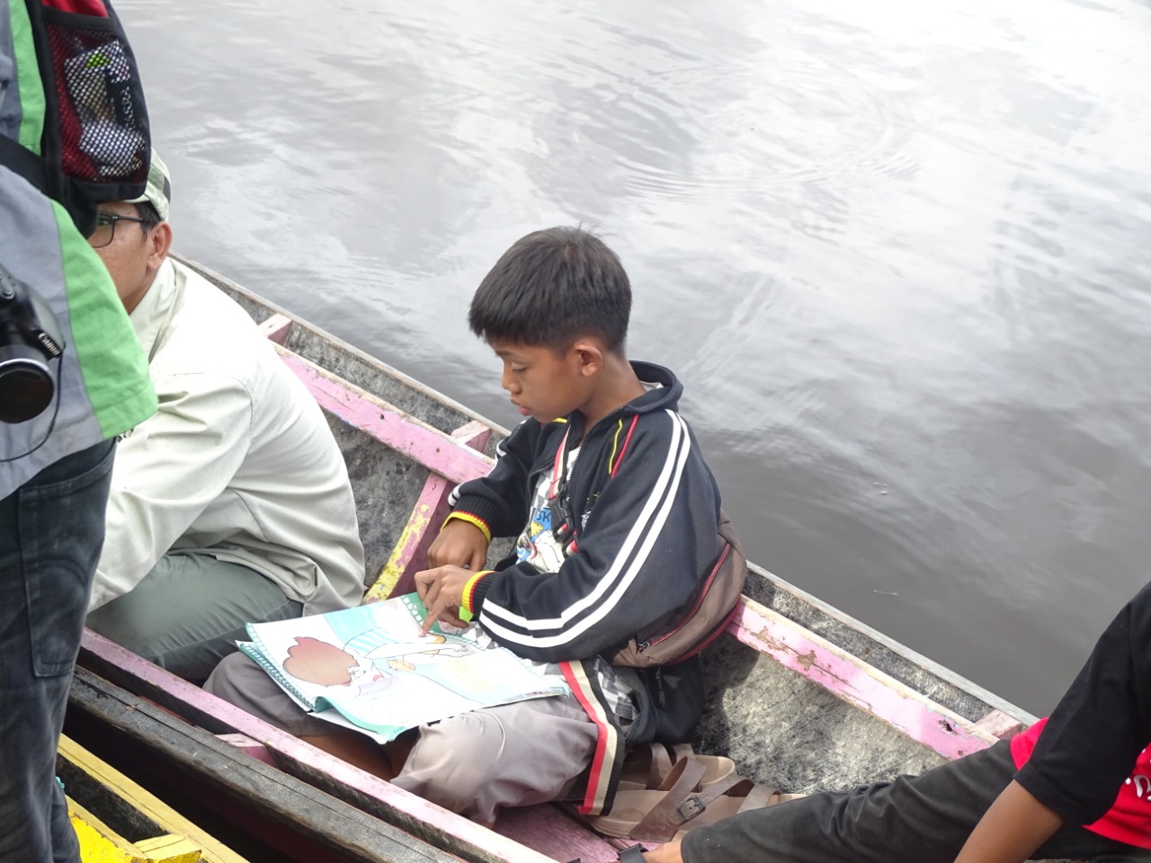 Seorang pelajar sedang membaca di atas perahu baca